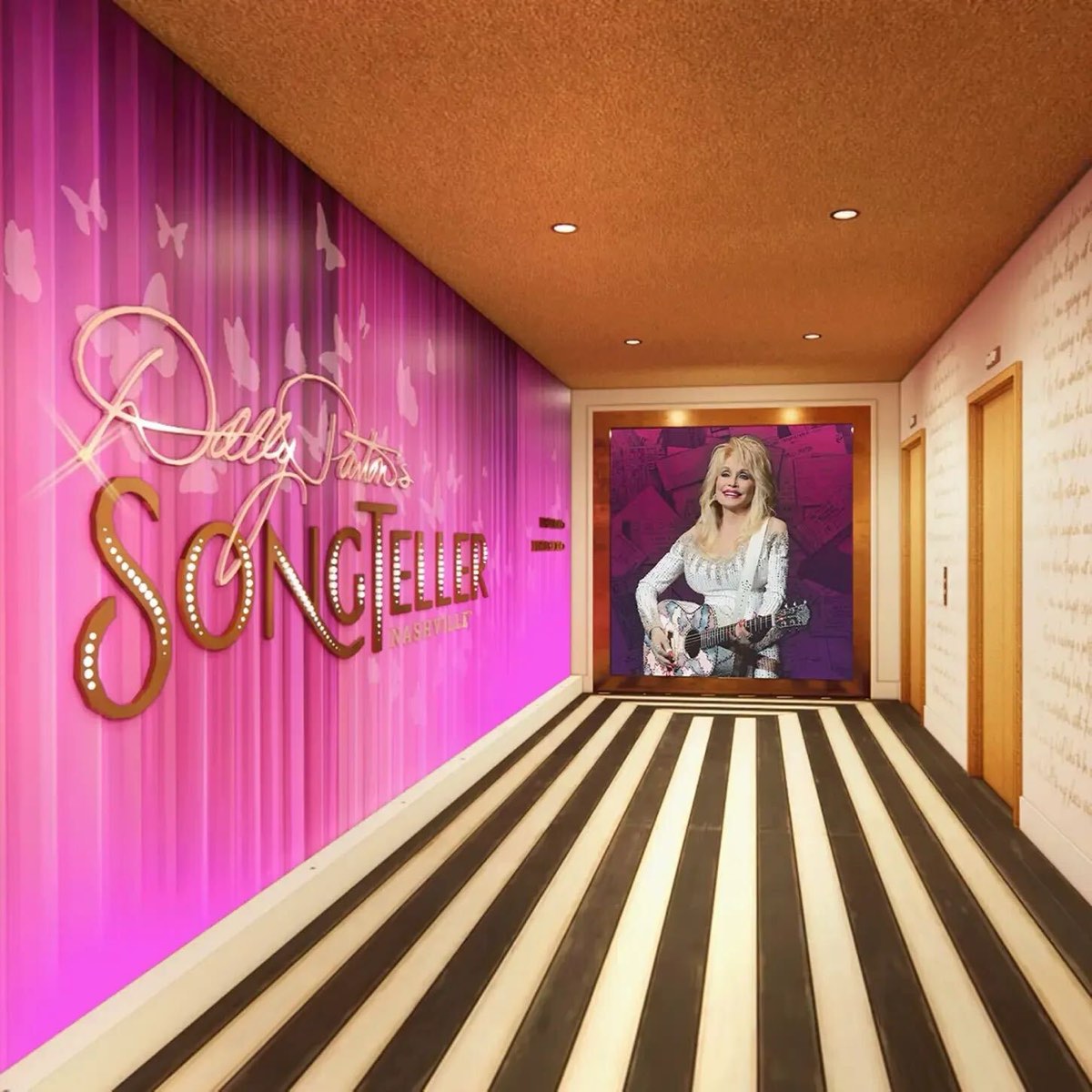 A hallway with a pink wall lit with the Dolly Parton's SongTeller sign, a striped floor and a portrait of Dolly with her guitar at the end