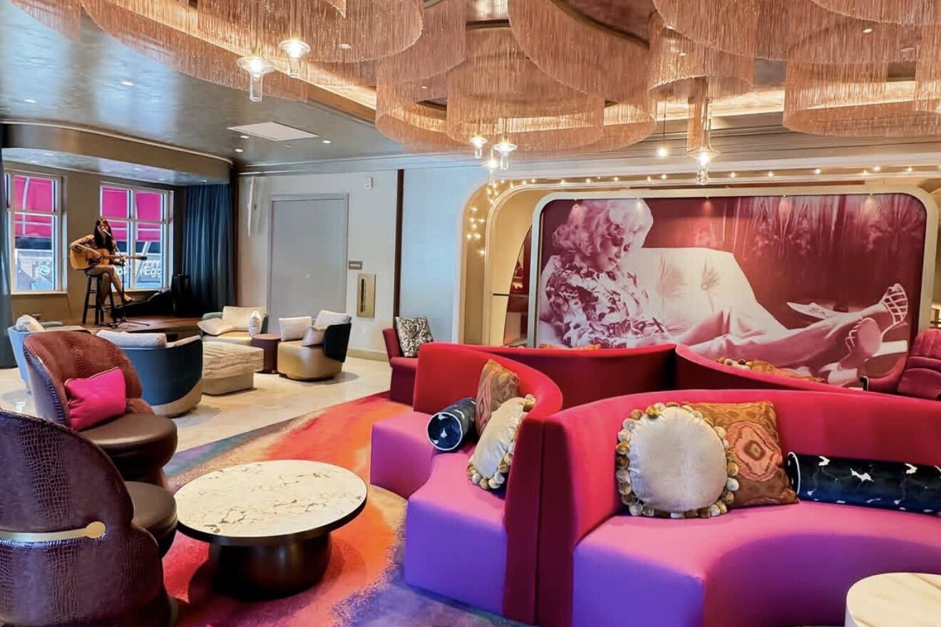 The hotel lobby: pink and red velvet sofas under fringed chandeliers, a large mural of Dolly Parton on the back wall and a singer with a guitar on a small stage by the windows