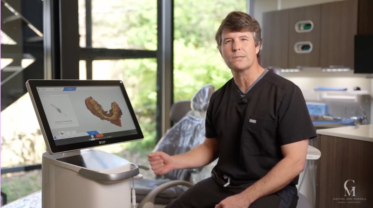 Dr. Murrell seated beside the office's CEREC scanner in an operatory