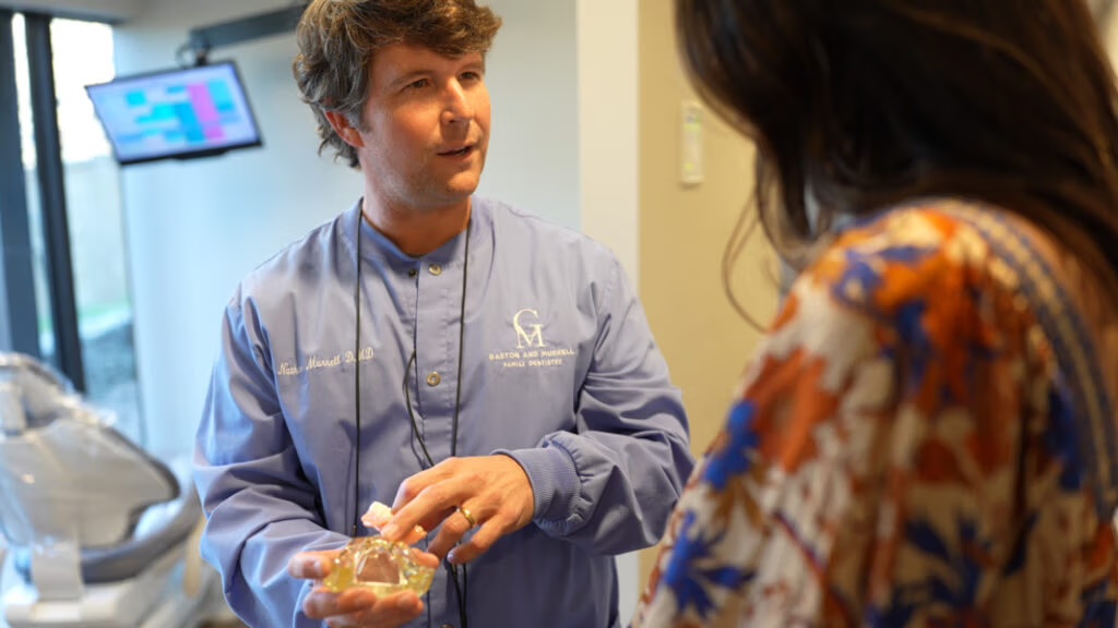 Dr. Murrell in GM-branded scrubs talking with a patient in the office