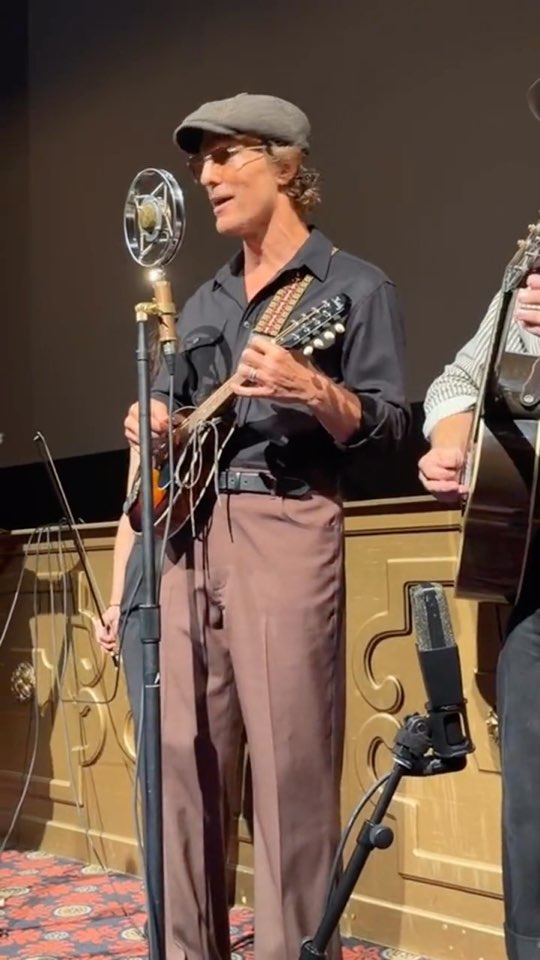 Matthew McConaughey singing at a vintage microphone on the Belcourt stage