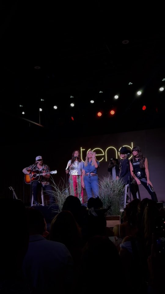 Singers on a small stage under a neon Trend sign